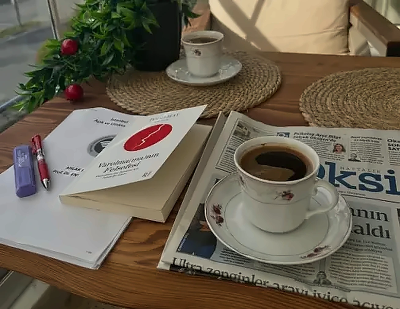 Kitaplar, kahve fincanları, not defteri ve gazete bulunan masa