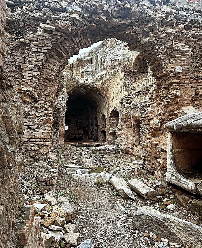 Yedi Uyurlar kalıntılarında tuğla kemerli bir geçit; arkada tonozlu mekânlar ve devrilmiş mermer bloklar